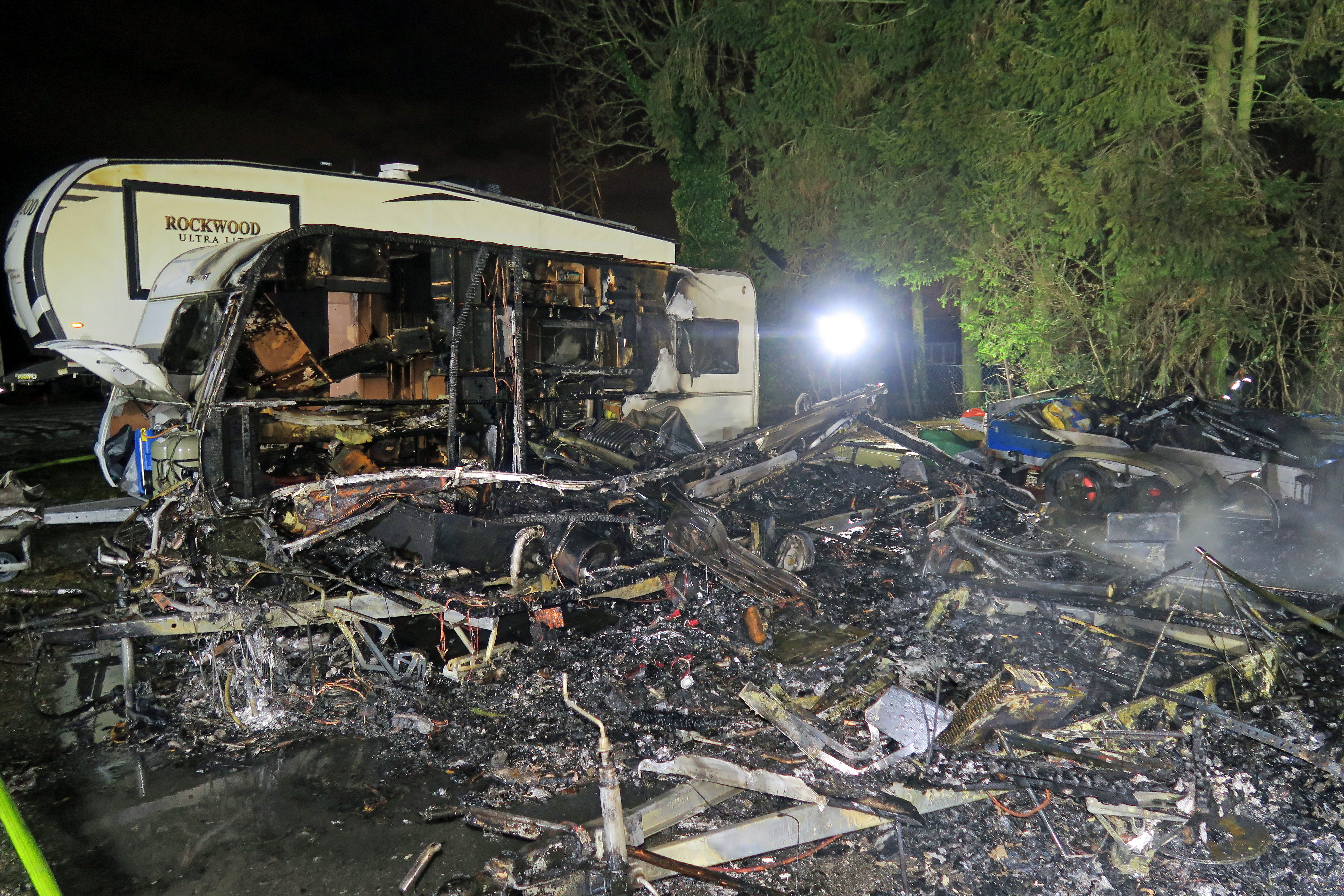 Ein ausgebrannter sowie ein durch Feuer beschädigter Wohnwagen stehen auf einem Platz.