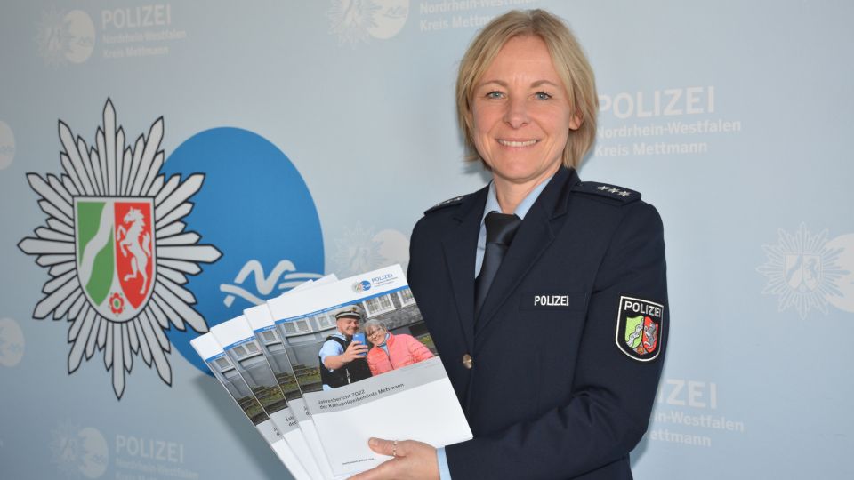 Polizeibeamtin in Uniform präsentiert die Broschüre des Jahreseberichtes