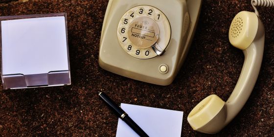 Ein altes Wähltelefon, daneben liegen Zettel und Stift
